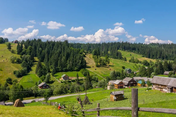 Beautiful countryside with neat rural houses standing on different sides of the road and farms with already cleaned and still lying dry hay. — Stock Photo, Image