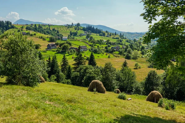 Una pintoresca vista de un pueblo rural situado en medio de verdes cadenas montañosas — Foto de Stock