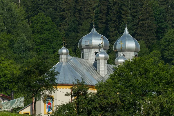 Церква з металевим дахом і куполами на фоні соснового лісу — стокове фото