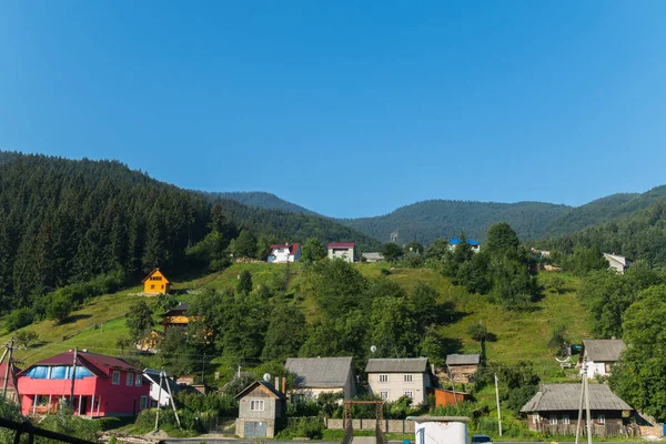 Village des Carpates avec de grandes maisons sur les collines dans le fond des forêts d'épinettes sur les montagnes — Photo