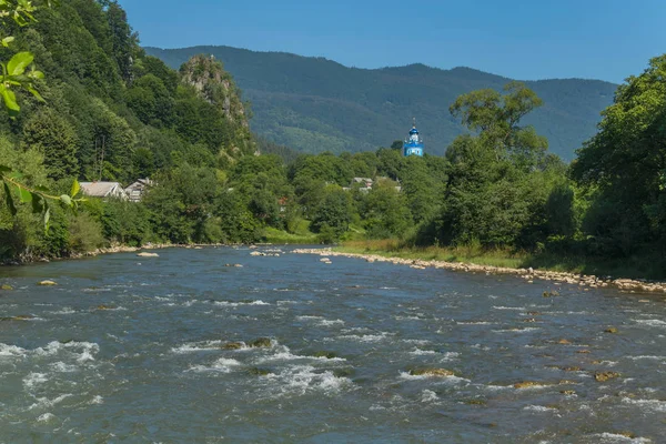 Hızlı dağ nehir arka planı mavi üstündeki kilise kilise, küçük evler ve rocky Dağları