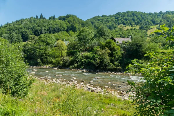 Taş evler, bankalar ile sığ bir nehir boyunca dağınık