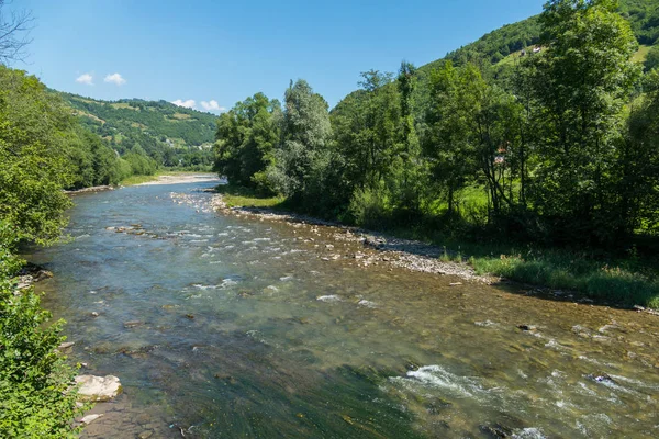 masmavi bir gökyüzü bulutlar ve dağlar ve yosun kaplı alt ile geçerli Nehri ile