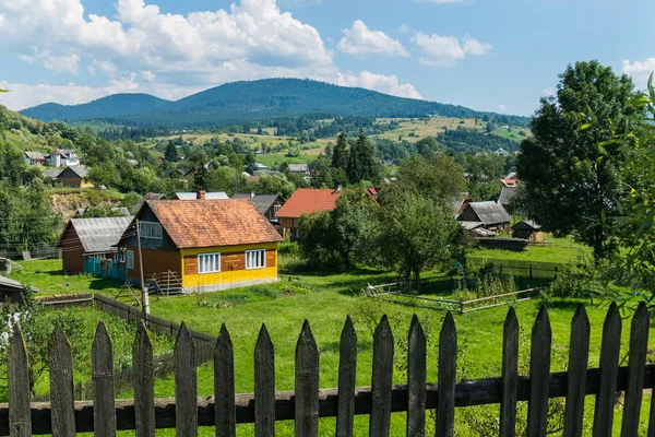 Alter Holzzaun vor dem Hintergrund eines ländlichen Bergdorfes mit hübschen Häuschen — Stockfoto