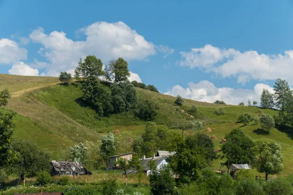 Маленькие старые сельские дома у склона зеленой крутой горы — стоковое фото