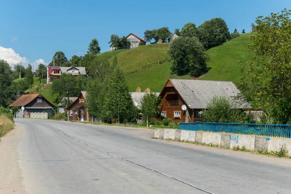 Eine breite asphaltierte Straße mit großen schönen Hütten und kleinen Bauernhäusern auf jeder Seite — Stockfoto