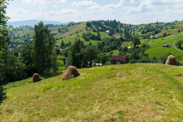 Yeşil bir eğim ile kalın bulutlar gökyüzü karşı ayakta evi üzerine yığılmış saman ile güzel bir görünüm.