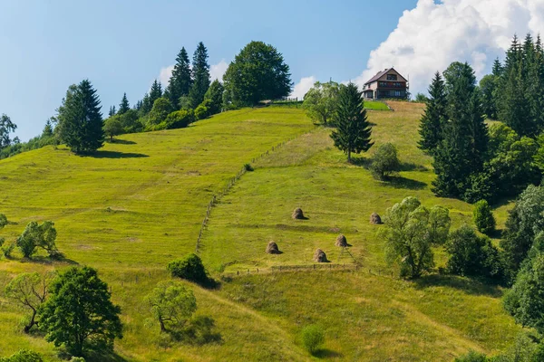 Eine Hütte auf einem grünen Hügel mit einem langen Zaun talabwärts — Stockfoto