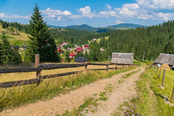 Kumlu toprak yol mesafe evler ahşap çitleri arasında çalışan kırsal kesimde.