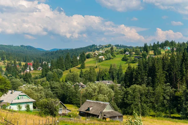 Ein Haus mit einem Dach aus Schiefer, und ein Haus mit einem Holzdach im Vordergrund zwischen den Bäumen und vielen anderen kleinen Häusern im Hintergrund — Stockfoto