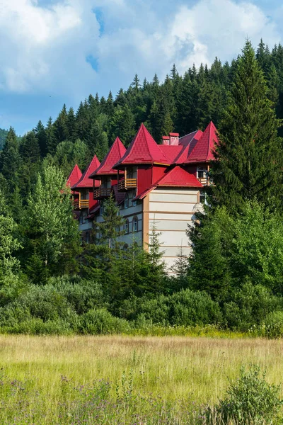 Un moderno edificio de hotel con hermosas torretas rojas de la arquitectura de baldosas balcones. Escondido en medio de árboles verdes de hermosa naturaleza . — Foto de Stock