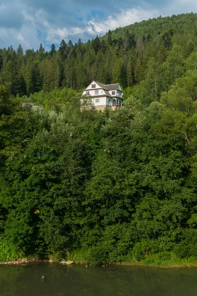 ön planda bir dağ nehir ile daha sık ormanın içinde 3 katlı ev