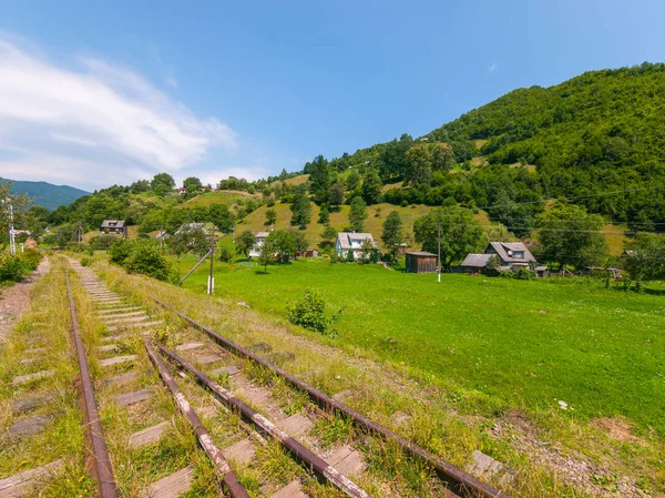 Eski demiryolu yakınındaki küçük kırsal konutlarında yüksek yeşil dağların arka planı