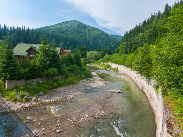 Stream s čistou vodou obklopující dům a má u sebe jeho vody směrem k hory v dálce — Stock fotografie