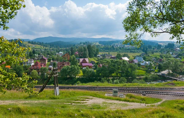 El ferrocarril que se extiende a lo largo del pueblo residencial y las hermosas montañas en la distancia —  Fotos de Stock