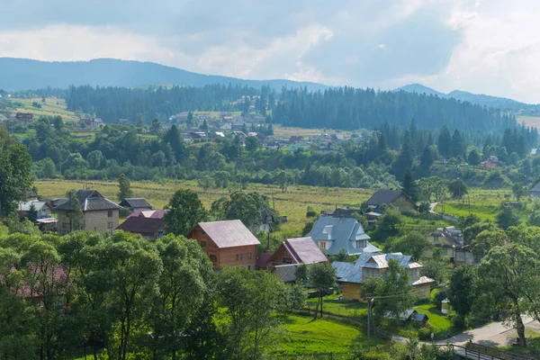 Ένα όμορφο και φιλόξενο χωριό βρίσκεται στους πρόποδες του μεγαλοπρεπή βουνά φόντο μια ομιχλώδη ουρανό — Φωτογραφία Αρχείου