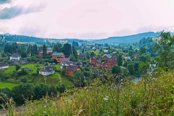 Nehir ve yeşil dağ yakın ahşap evler ile küçük bir köy üstten görünüm