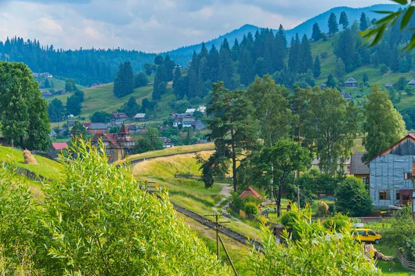 Die Eisenbahn biegt vor dem Hintergrund des Dorfes und der malerischen Natur ringsum ab. — Stockfoto