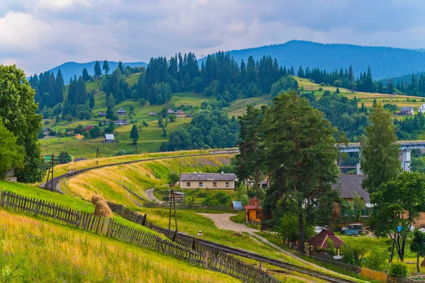 Ein Dorf mit schönen Häusern und schöner Natur, durch das eine Eisenbahn verlegt wird — Stockfoto