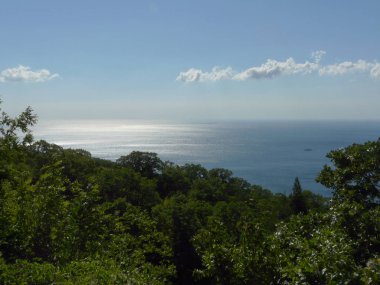 Uzak mavi bir gökyüzü ve nadir bulutları ve sahile yelken bir iyot tekne ile denizin ufuk çizgisi uzanan muhteşem bir manzara.