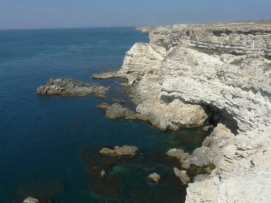 Bir boş, taş plaj derin, karanlık bir deniz üzerinde yüksek bir uçurum ile gri taştan