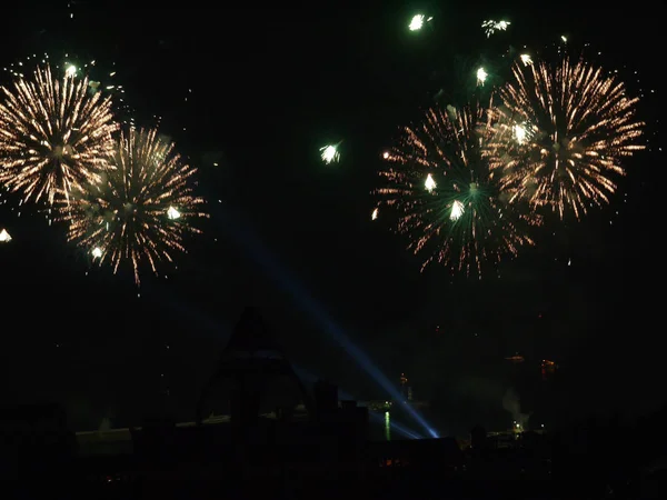 Karanlık gece gökyüzüne bir festival selam yerden daha büyük etkisi için ışık ışınları tarafından aydınlatılmış.