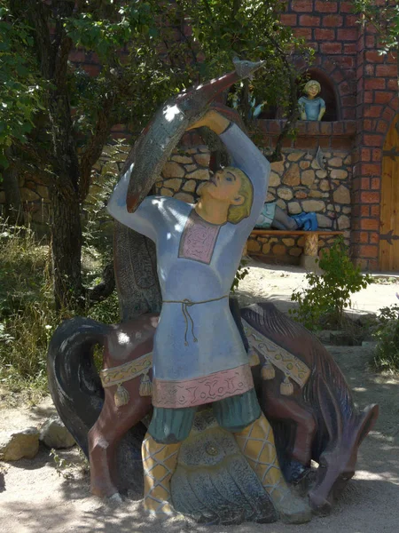 Veelkleurige sculptuur van een sprookjesachtige karakter met een paard tegen de achtergrond van een groene boom — Stockfoto
