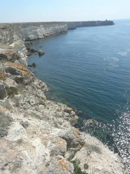 Derin sonsuz deniz, mavi gökyüzü kayalık dağ kıyıya yıkama