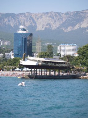 Bir mavna ayakta bir iskele üzerinde şeklinde bir restoran. Güzel dağlar zemin karşı cam duvarlı yüksek otel.