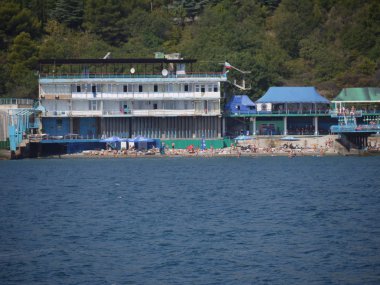 İnsanlar denize sıfır sahil şeridinin güzel manzarasını plaj altyapı ve yeşil yamaç ortasında bir sıcak yaz gününde.