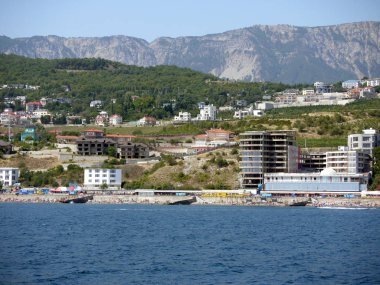 Şık otel kompleksleri ve kayalık dağ arka planda büyük plajları ile kıyı alanı