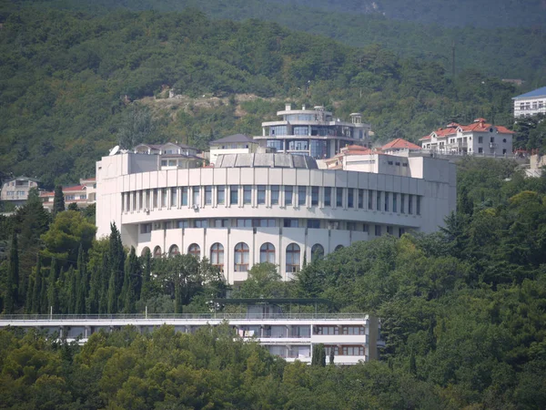 Ένα λευκό ξενοδοχείο κτίριο στη μέση ενός καταπράσινου βουνού λαμβάνει πολλοί τουρίστες στα διαμερίσματά τους — Φωτογραφία Αρχείου