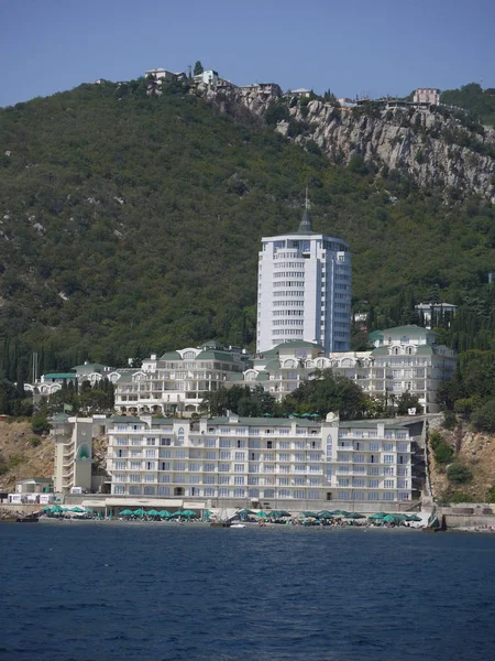 Ένα όμορφο ξενοδοχειακό συγκρότημα με την παραλία μπροστά στη θάλασσα, στους πρόποδες από ένα ψηλό πράσινο βουνό — Φωτογραφία Αρχείου