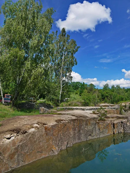 Sten dammen shore mot bakgrund av björkar och moln — Stockfoto