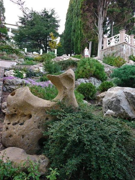 Камені в парку на схилі, зроблені у вигляді різних фігур серед кущів з зеленню — стокове фото