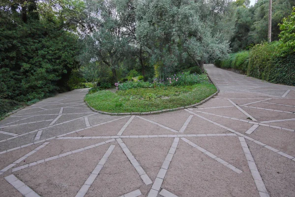 Il marciapiede nel parco intorno alla aiuola con un modello asimmetrico di piastrelle. Puoi fare una passeggiata, rilassarti con gli amici — Foto Stock