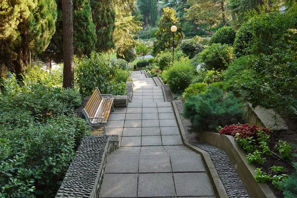 Una escalera con escalones y macizos de flores alrededor, entre el parque verde, y alrededor son linternas — Foto de Stock