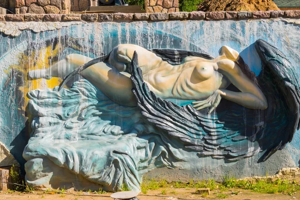 Murade med en ovanlig skulptur av en flicka med svarta vingar på en blå bakgrund — Stockfoto