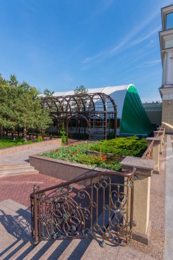 Mükemmel manzara çiçek yatak, ağaçlar ve mavi gökyüzü ile parkta. Adımları yakınındaki güzel kıvırcık parmaklıklar sadece bunları tamamlayıcı