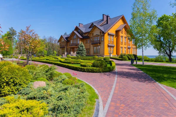 Camino de piedra roja a una casa de madera con un hermoso paisaje de jardín — Foto de Stock