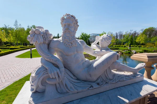 Staty av Dionysos med en bukett av druvor på bakgrunden av en grön flotta park med en djup, ren damm. Symbol för vinframställning — Stockfoto