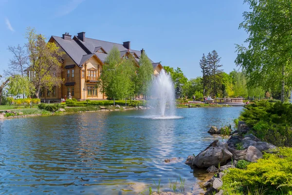 Zona de parque con una gran casa de madera, un lago y fuentes en ella. Mezhigorye, Ucrania — Foto de Stock