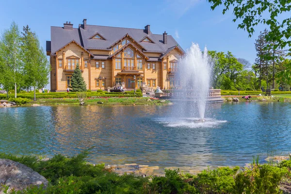 Personnes se reposant près d'une maison sur la rive verte d'un étang avec une fontaine — Photo