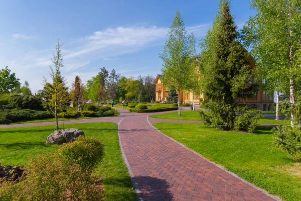 Park je pěší zóna s krásné zelené plochy a cesty vedoucí k obrovské dřevěného domu. Mezhigorye, Ukrajina — Stock fotografie