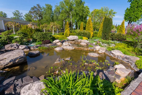 Pequeño estanque decorativo en un parque con enormes piedras — Foto de Stock