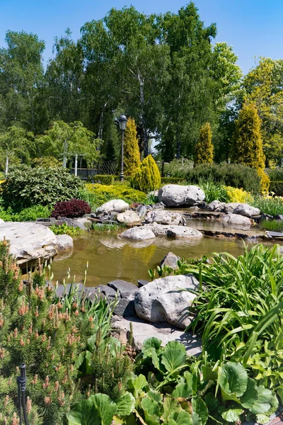 绿色装饰湖与岩石和各种各样的灌木在大公园区域的背景下 — 图库照片