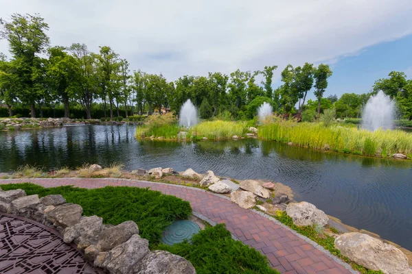 Каскад фонтанов на озере с скалистыми берегами и островом посреди парка — стоковое фото