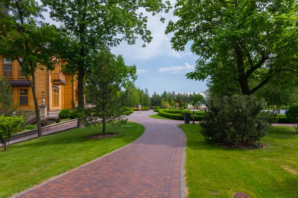 O beco do parque com um belo gramado verde ao longo dele, levando a uma luxuosa villa de madeira — Fotografia de Stock
