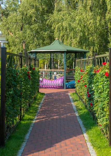 Beco levando a um belo gazebo decorativo com um telhado verde e uma cerca — Fotografia de Stock