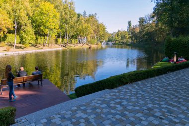 İnsanlar arka planı yeşil ağaçlar küçük parkta gölün kıyısında üzerine getirin
